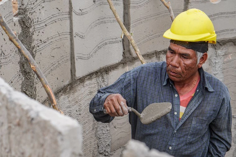 Un trabajador construye una pared con bloques y mortero